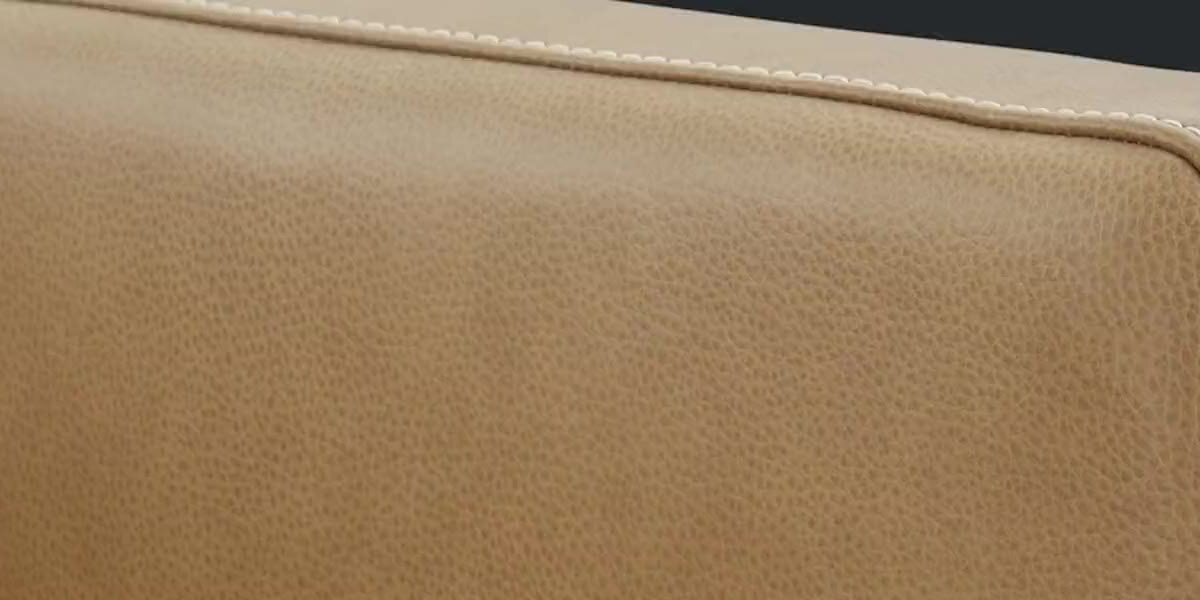 Close-up of pebble-grain leather and contrast stitching on a Violino sofa armrest